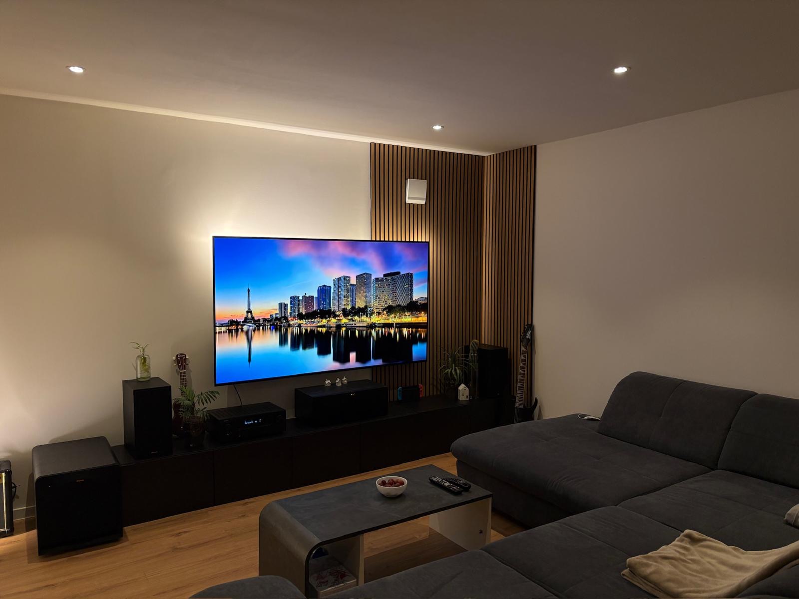 Modern gestaltetes Wohnzimmer mit Holz-Akustikpaneelen und hochwertigem Innenausbau